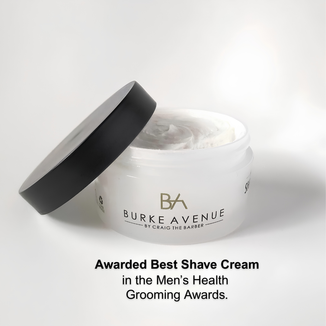 A white jar of Burke Avenue By Craig The Barber shave cream with its black lid leaning against it, shown on a light gray background with award text below.